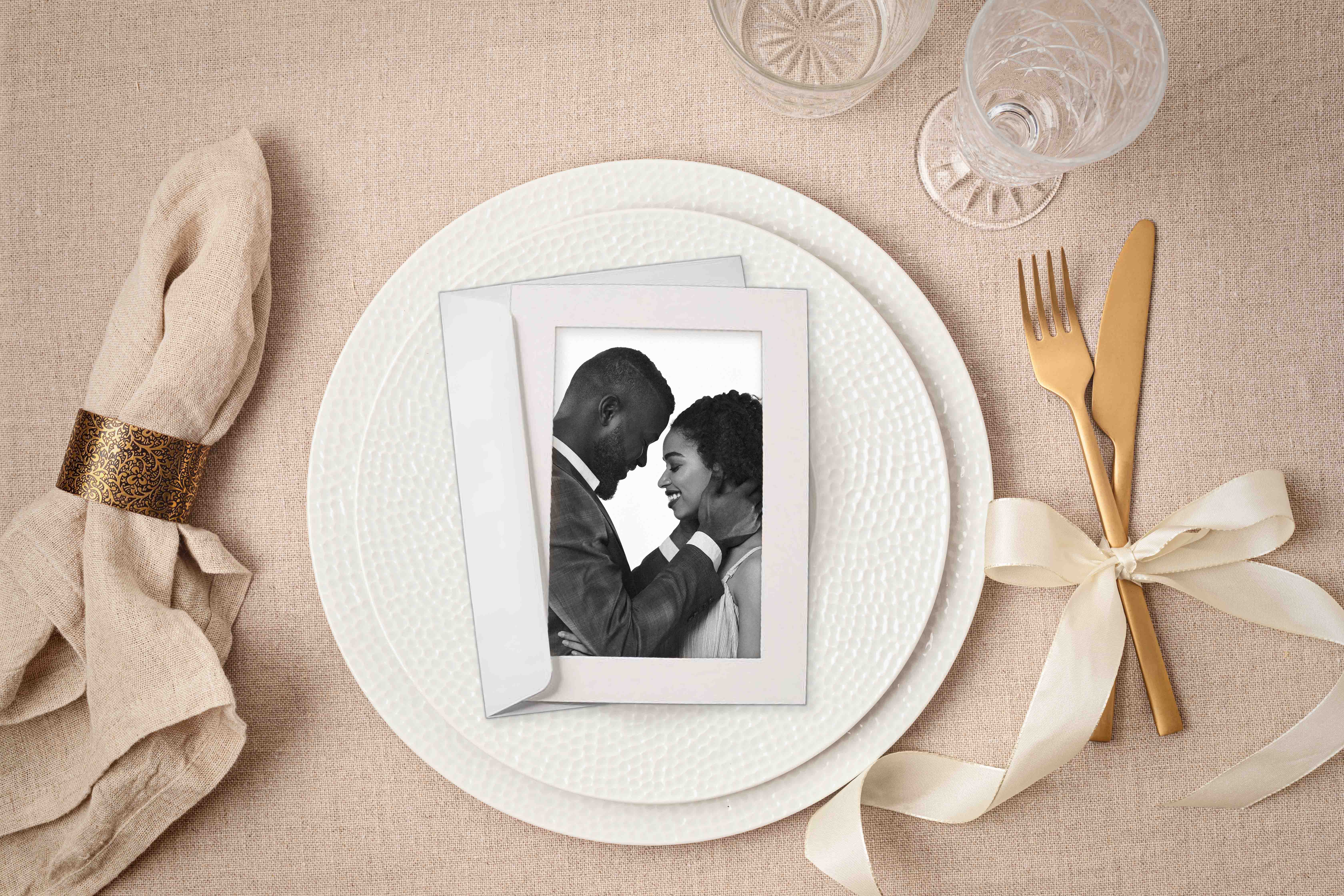Photo in paper frame on table setting with golden cutlery and porcelain plate